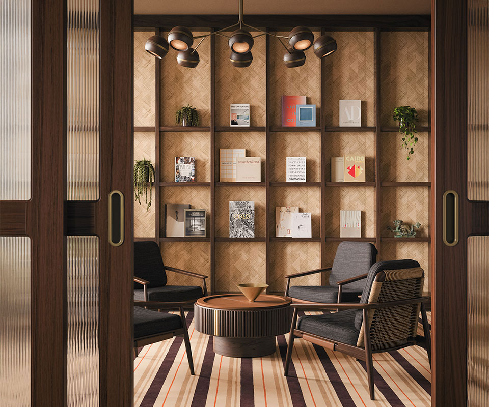 Four Adam Armchairs upholstered in black fabric with rattan details arranged in a circle around a Robert center table in smoked walnut wood with leather and brushed brass accents. The living room is warmly lit, featuring a bookcase backdrop illuminated by a Fleming suspension lamp, framed by two fluted glass doors.