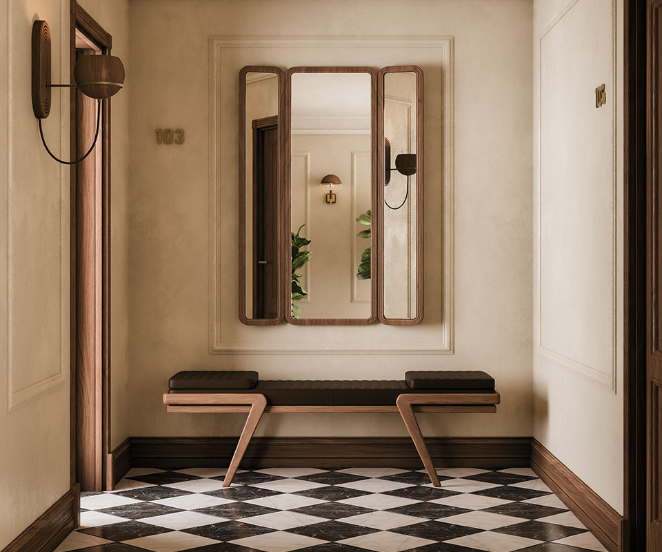 Tom folding mirror in a hotel corridor, featuring upholstered doors, leather handles, and an interior mirror. The floor displays a diamond checker pattern. Below the mirror is the Milton Bench, with an oak structure and leather seat. Flaming wall lamp and Faraday wall lamp in smoked walnut wood complete the setting.