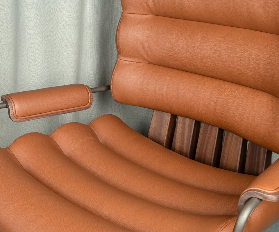 Close-up of the Thomas I office chair, highlighting the rich texture of orange genuine leather and the warmth of smoked walnut wood.