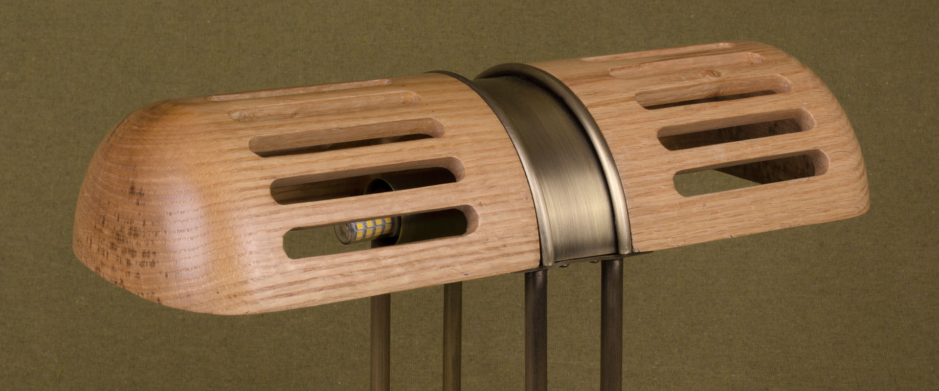 Detail of the Turing Table Lamp shade, crafted in natural oak and aged brushed brass, set against a green background.